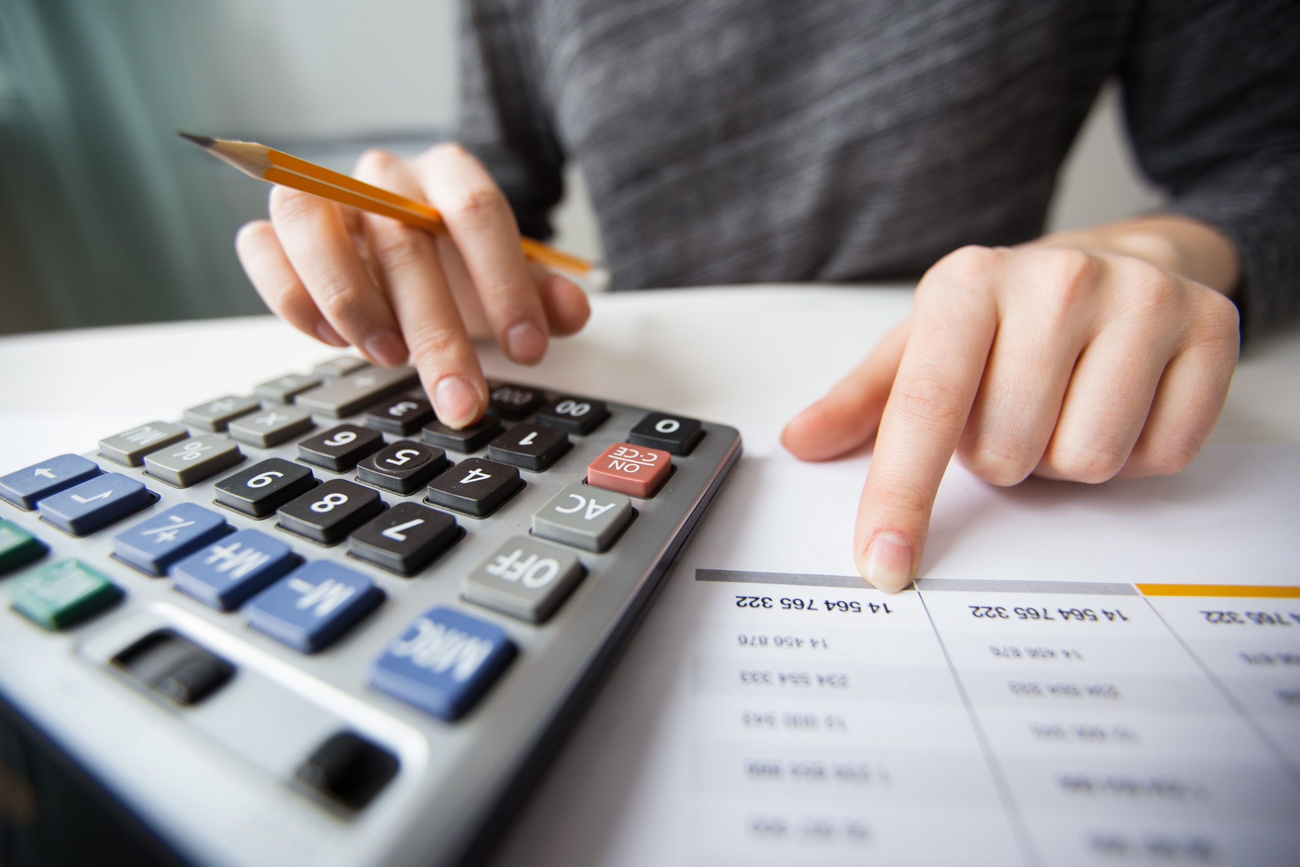 Closeup of accountant counting on calculator and working with table
