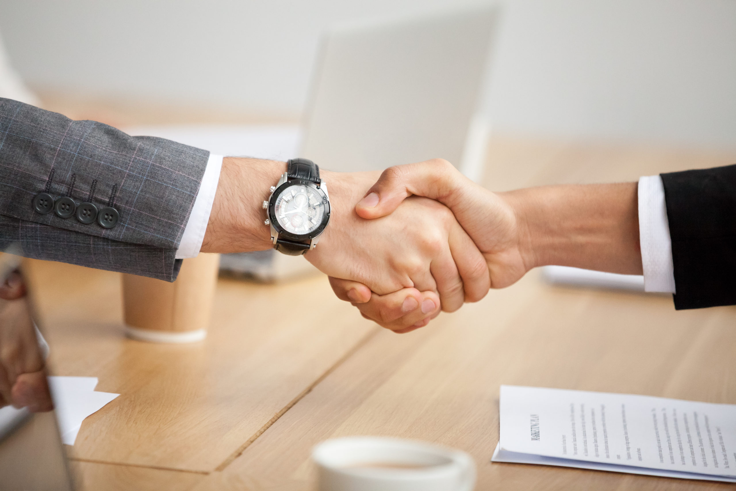 Close up view of handshake, two businessmen in suits shaking hands as concept of trust, good partnership deal, signing contract agreement at meeting, gratitude for help support in business